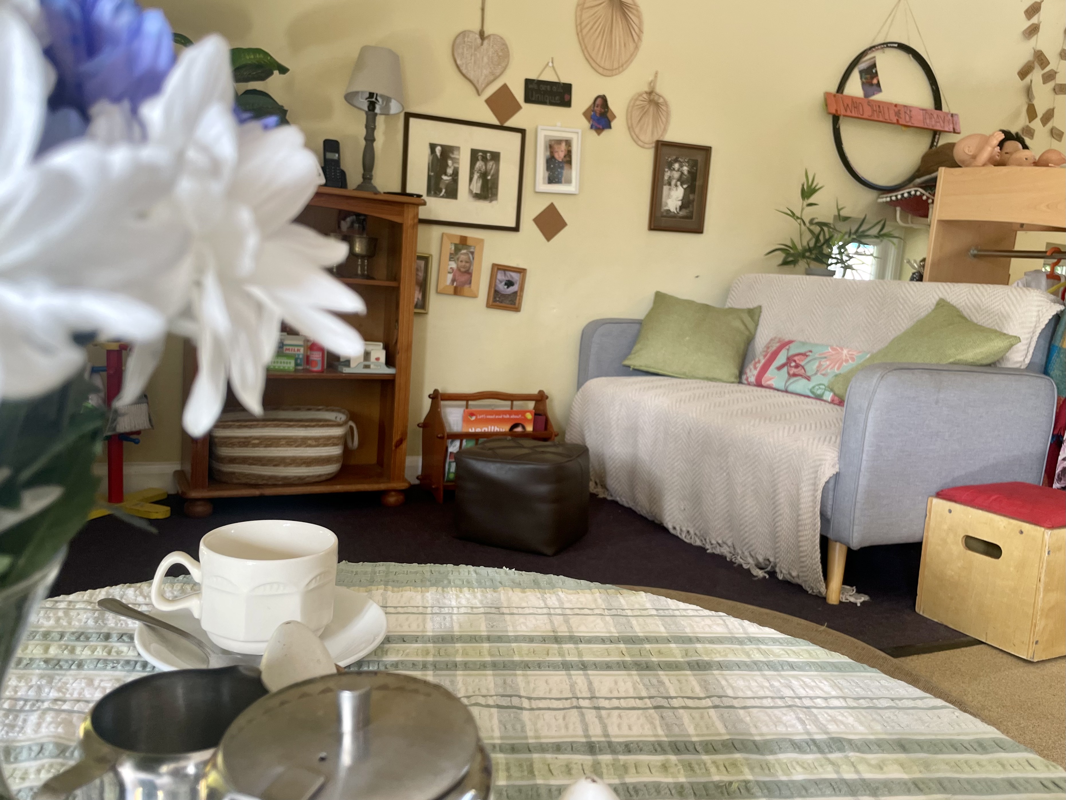 Photo of a 'home corner' inside a preschool with a sofa in the background and a table in the foreground