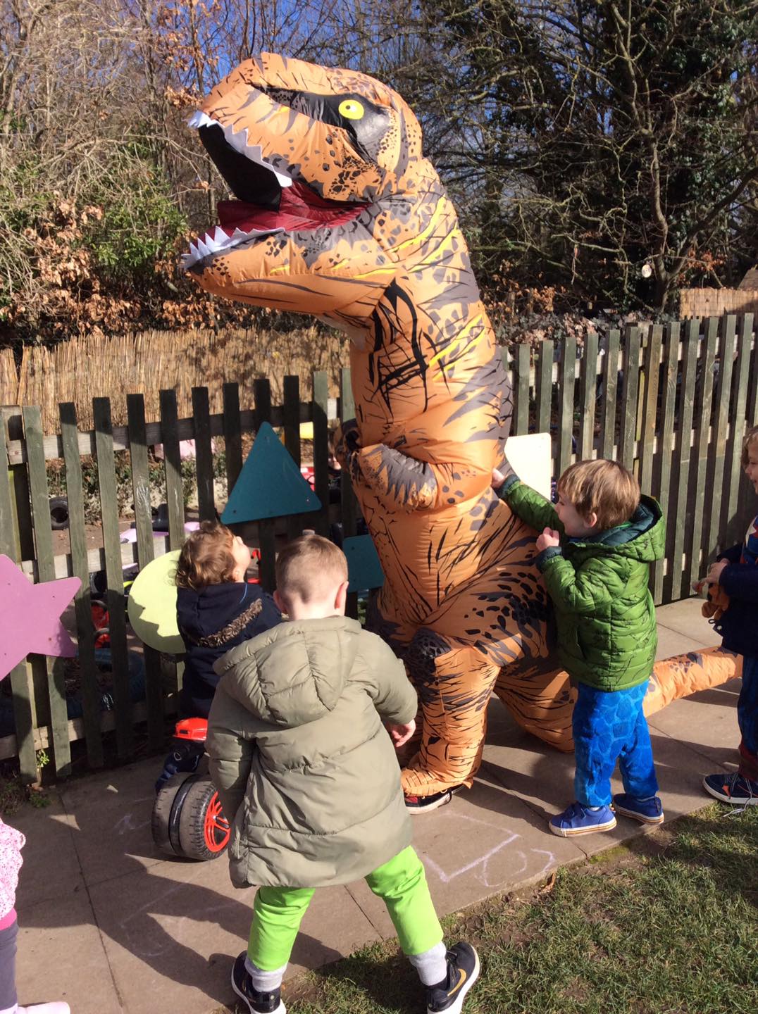 Child playing with someone in a large inflatable dinosaur costume