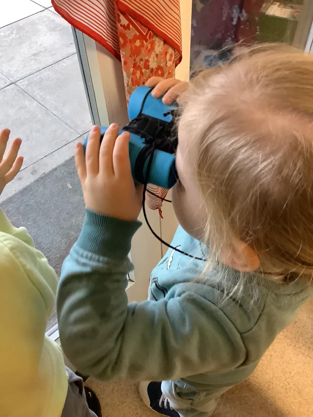 Toddler. girl, looking through toy binoculars off out of frame