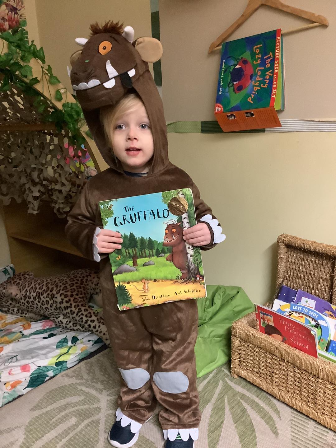 Child in a gruffalo outfit holding a copy of the book