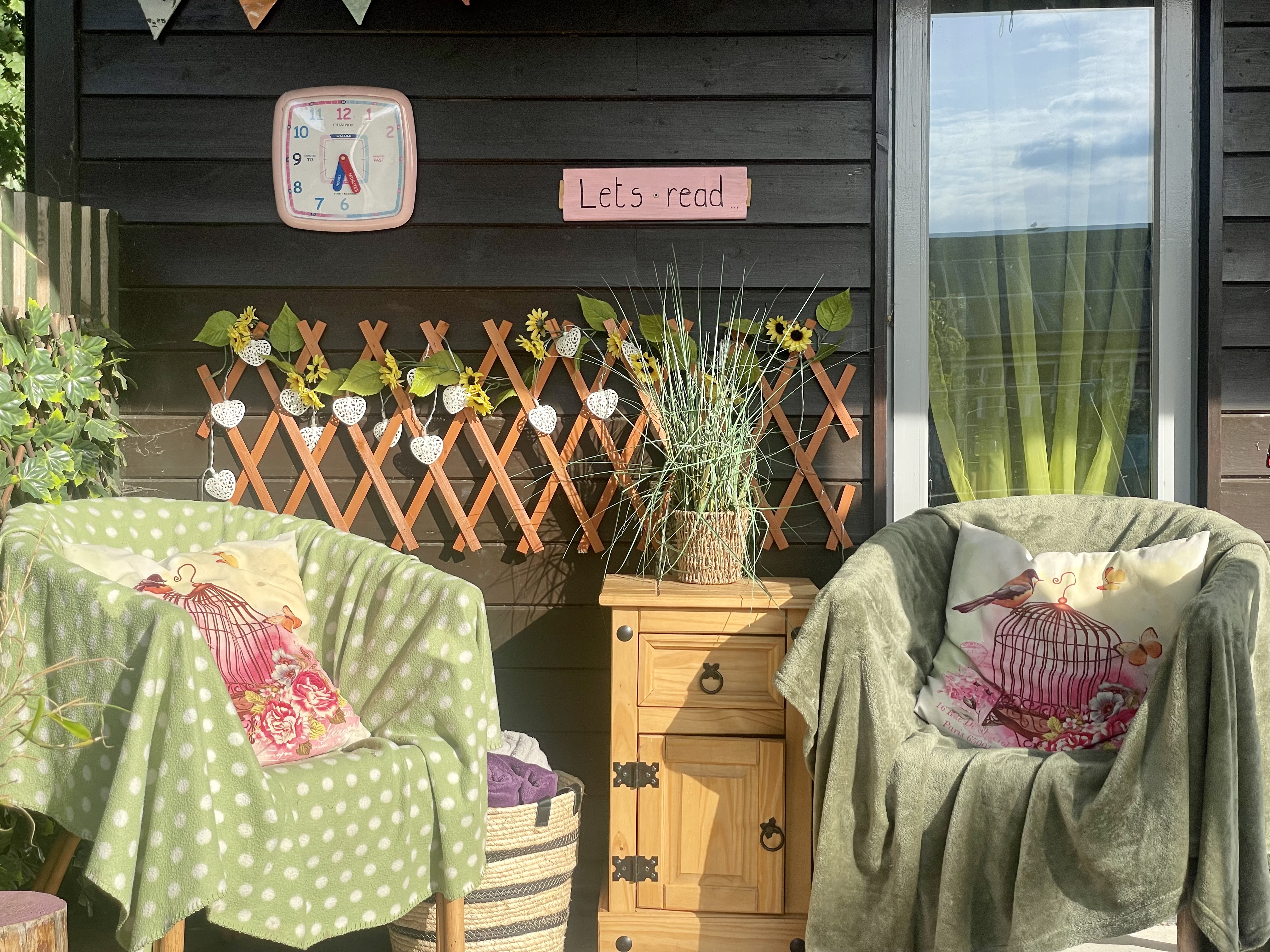 Two chairs, a side table and some flowers in an outdoor reading corner